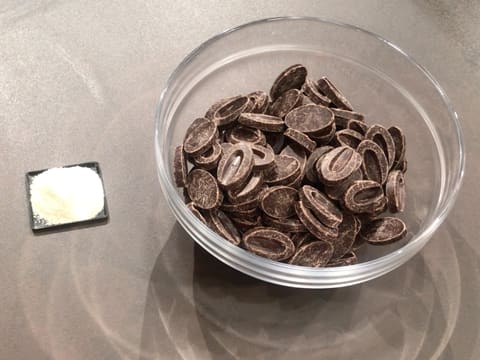 Un saladier en verre rempli de fèves de chocolat noir et d'un peu de beurre de cacao Mycryo est posé sur le plan de travail