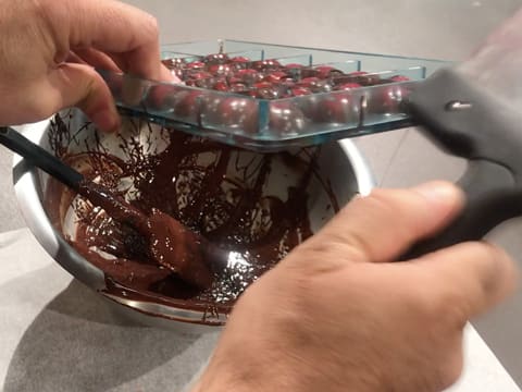 Le moule chocolat demi sphère retourné au dessus du cul de poule est tapoté avec la spatule à chocolat