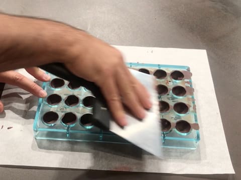 La surface du moule chocolat demi sphère est raclée avec la spatule à chocolat