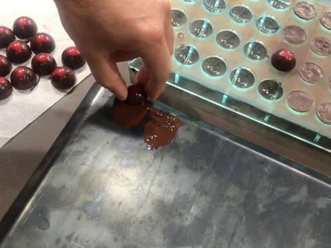 Une demi sphère au chocolat et caramel framboise est partiellement fondue sur sa surface plane sur une plaque de cuisson chaude