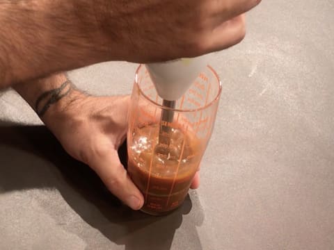 Le caramel mangue est mixé à l'aide d'un mixeur plongeant dans le verre doseur