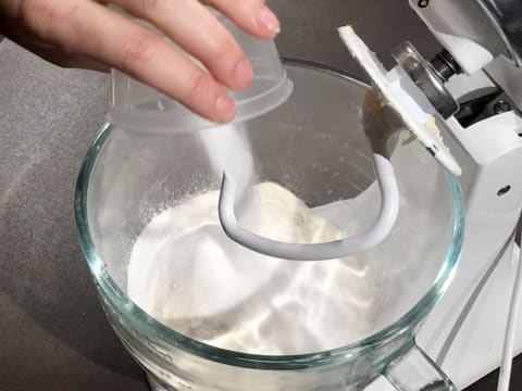 Ajout du sel fin sur le sucre en poudre et la farine dans la cuve du batteur qui est muni de l'accessoire crochet