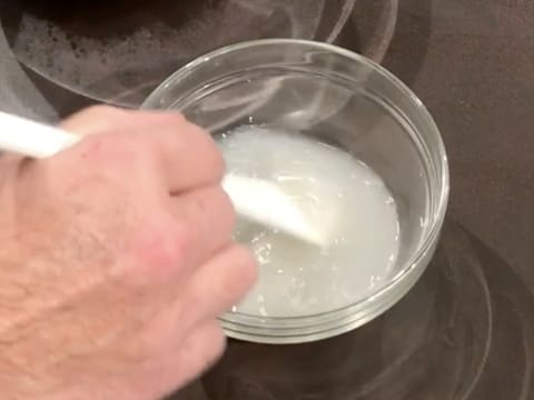 L'eau et la levure de boulanger fraîche sont mélangées ensemble avec une spatule, dans le petit bol