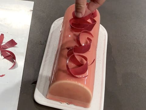 Les décors en chocolat à la framboise sont disposés sur la bûche glacée