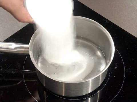 Ajout du sucre en poudre dans l'eau et le sirop de glucose, dans la casserole