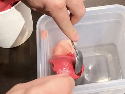 La cuillère à soupe de sorbet framboise est déposée à côté du sorbet litchi