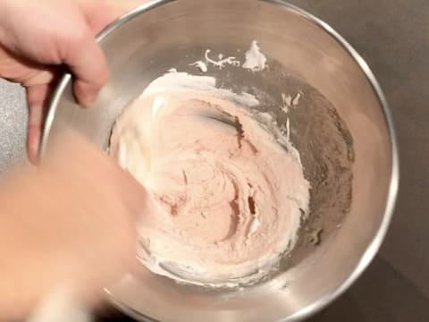 Mélange de la meringue Italienne, de la préparation à macaron et du colorant rouge dans le cul de poule, avec la spatule