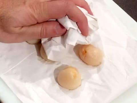 Des litchis sont épongés entre deux feuilles de papier absorbant