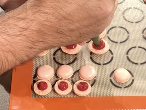 La moitié des coques à macaron sont garnies de confit de framboise