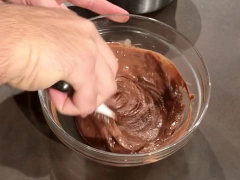 Le lait est incorporé dans le chocolat fondu à l'aide de la spatule maryse