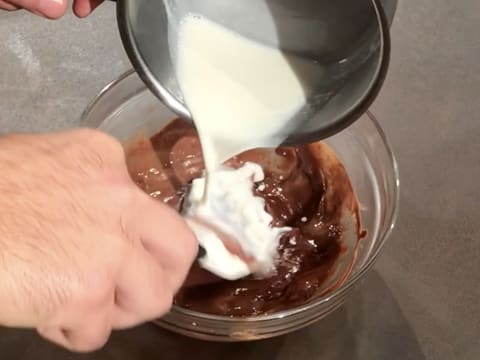 Un peu de lait est versé dans le chocolat au lait fondu tout en mélangeant avec la spatule maryse