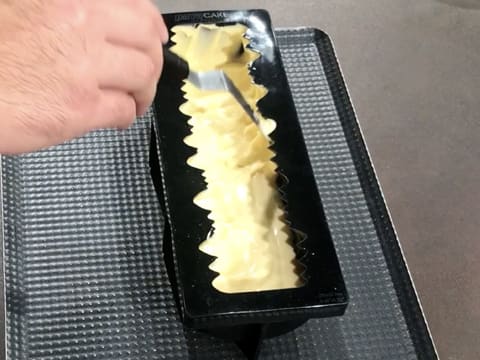 La mousse Inspiration passion est remontée sur les bords du moule silicone à l'aide d'une mini spatule coudée