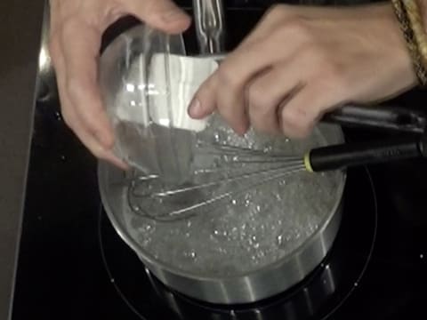 Le sirop de glucose est versé sur le sirop qui est en ébullition dans la casserole placée sur la plaque de cuisson