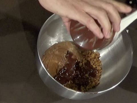 Ajout du mélange chocolat et beurre de cacao fondus sur le praliné noisette et le spéculoos concassé dans la cuve du batteur