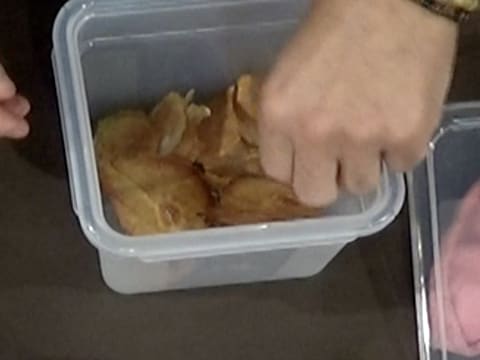 Les chips de poire sont dans une boîte hermétique et le Chef en attrape une avec les doigts