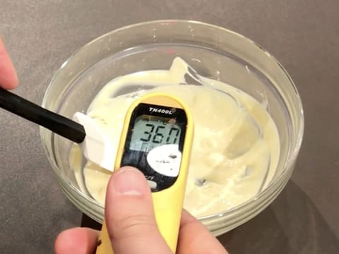 À L'aide d'un thermomètre à visée laser, prise de la température du chocolat blanc fondu dans le bol, qui titre 36,0°C