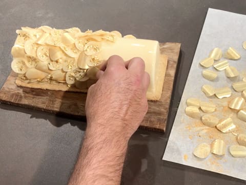 Les pastilles de chocolat blanc dorées et pailletées sont déposées sur la bûche glacée