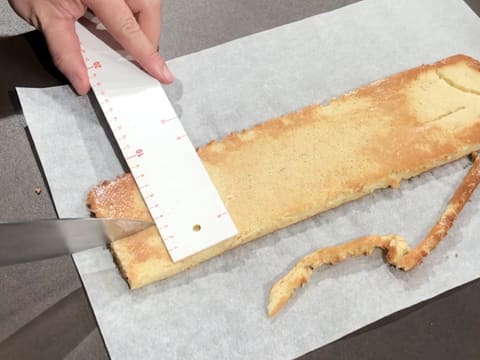 Une bande de biscuit aux pignons de pin est mesurée à l'aide d'une règle graduée