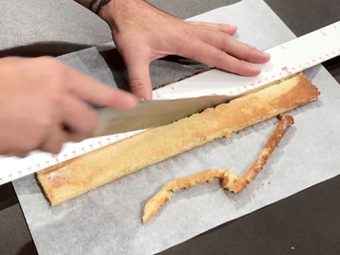 La bande de biscuit aux pignons de pin est détaillée à l'aide du couteau et de la règle graduée