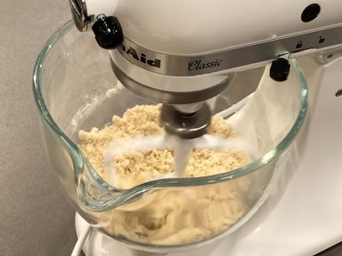 Mélange des éléments dans la cuve du batteur électrique avec l'accessoire feuille et formation d'un sablage comme un crumble