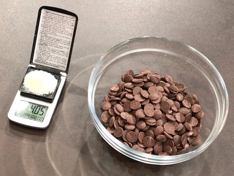 Le beurre de cacao Mycryo est placé sur une petite balance électronique de précision et les pistoles de chocolat au lait sont versées dans un saladier