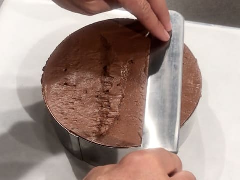 La surface de la mousse au chocolat est lissée avec une grande spatule métallique coudée