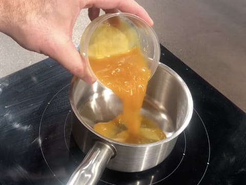 La purée de fruit de la passion est versée dans une casserole qui est placée sur une plaque de cuisson