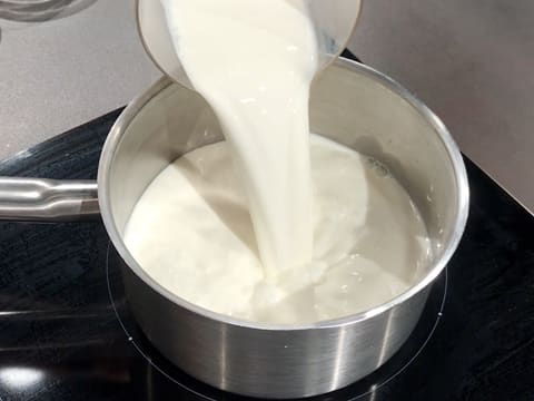 Le lait est versé dans la casserole qui est placée sur la plaque de cuisson