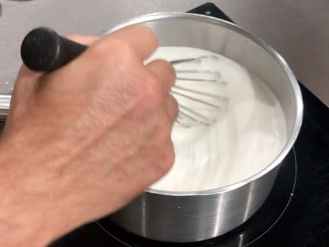 Mélange au fouet de la préparation lactée qui est en train de cuire dans la casserole