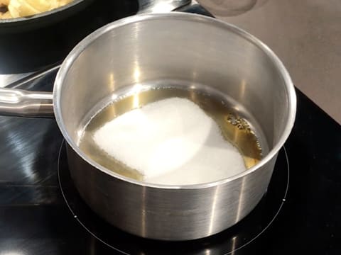 Le sucre en poudre dans la casserole commence à fondre pour se transformer en sirop