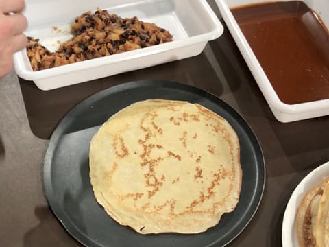 Une crêpe est placée sur une plaque à pâtisserie ronde