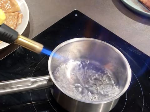 Le Cointreau est flambé dans la casserole, avec la flamme d'un chalumeau de cuisine