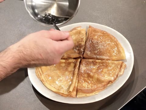 Le Cointreau chaud est versé sur l'assiette de crêpes