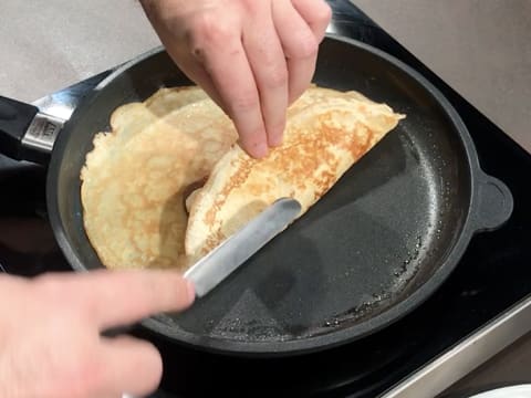 Un des côtés de la crêpe est replié sur le milieu, à l'aide d'une petite spatule métallique coudée