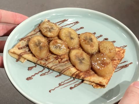 Obtention de la crêpe chocolat/banane décorée de filaments de pâte à tartiner et de rondelles de banane cuite