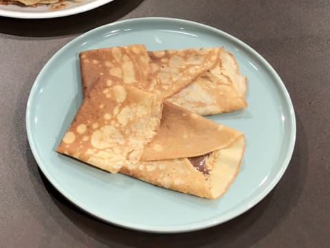 Deux crêpes pliées sont placées dans une assiette de service