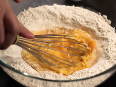 Les oeufs entiers sont mélangés au fouet, au centre de la farine