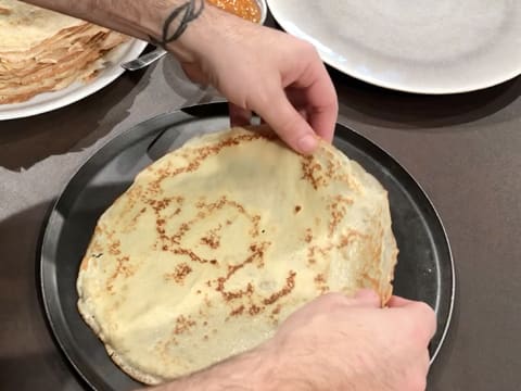 Une crêpe est déposée sur une plaque à pâtisserie ronde