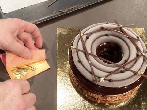 Des pointes de feuille d'or sont déposées sur l'entremets au chocolat de Pâques, avec la petite pince à dresser