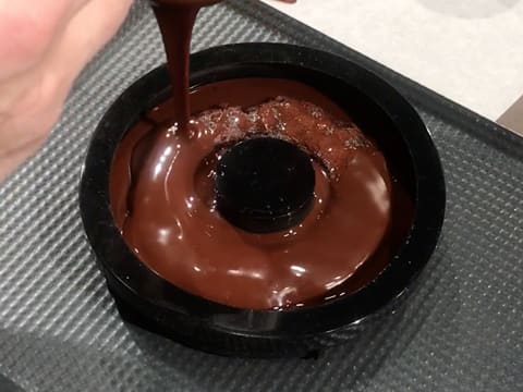 La ganache chocolat/tonka est versée dans le moule silicone, sur le biscuit chocolat