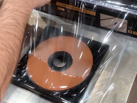 Le moule spirale en silicone et le crémeux au chocolat sont filmés au contact avec une feuille de papier film