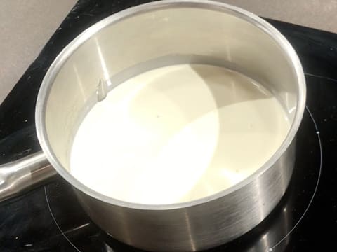 Une casserole contenant de la crème liquide est placée sur la plaque de cuisson