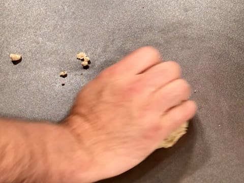 Formation d'une boule de pâte à streusel noisette avec la main, sur le plan de travail