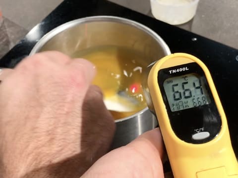 Prise de la température de la préparation dans la casserole à l'aide d'un thermomètre à visée laser qui affiche 66,4°C