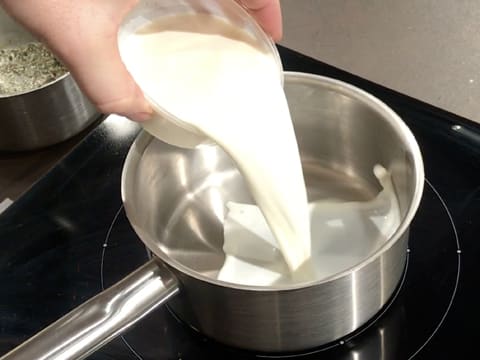 Le lait est versé dans une casserole qui est placée sur la plaque de cuisson