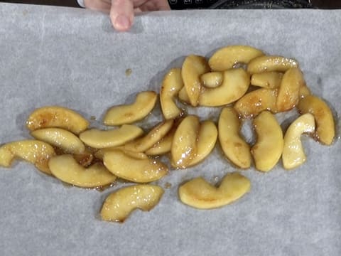 Les lamelles de pomme cuites sont sur la feuille de papier sulfurisé