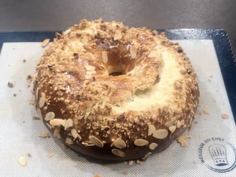 Obtention de la galette des rois briochée cuite et dorée, sur une plaque à pâtisserie recouverte d'un tapis de cuisson en silicone qui est posée sur le plan de travail