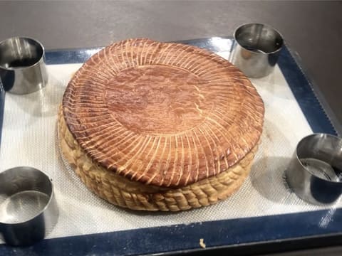 Obtention d'une galette des rois cuite et dorée sur la plaque à pâtisserie recouverte du tapis en silicone et de quatre petits cercles à mousse