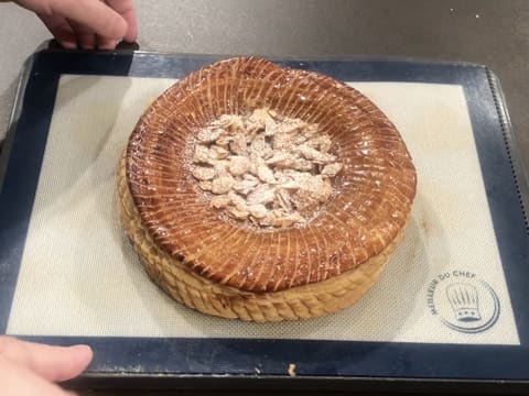 Obtention d'une galette des rois décorée d'amandes effilées caramélisées et de sucre glace qui forment un cercle en son centre