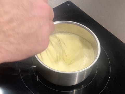 Mélange au fouet de la crème qui est en train de cuire dans la casserole